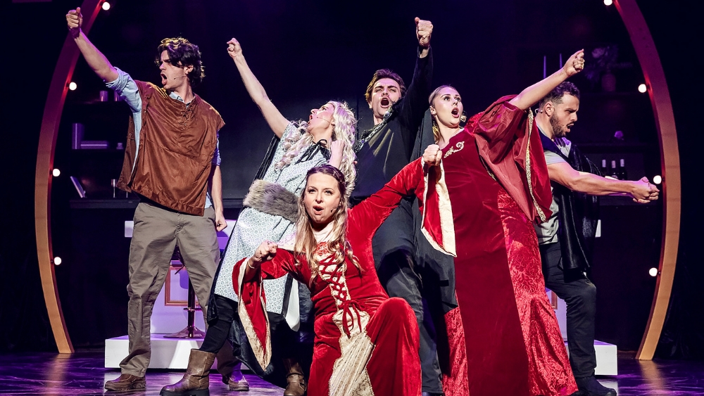 Cast of 'Thrones! The Musical Parody' performing on stage, dressed in elaborate, humorous Westeros-inspired costumes.