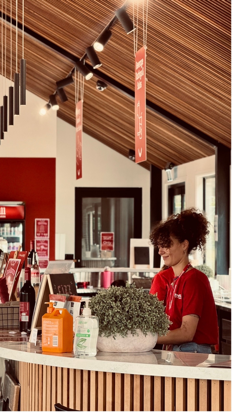 CherryHill Orchards staff member smiling behind the farmgate counter at the Coldstream location