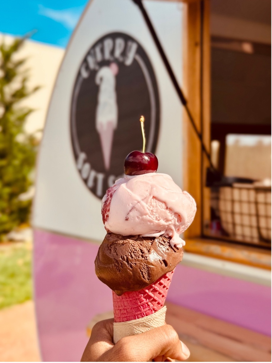 Cherry chocolate and pink ice cream in a pink waffle cone with cherry on top at CherryHill Orchards