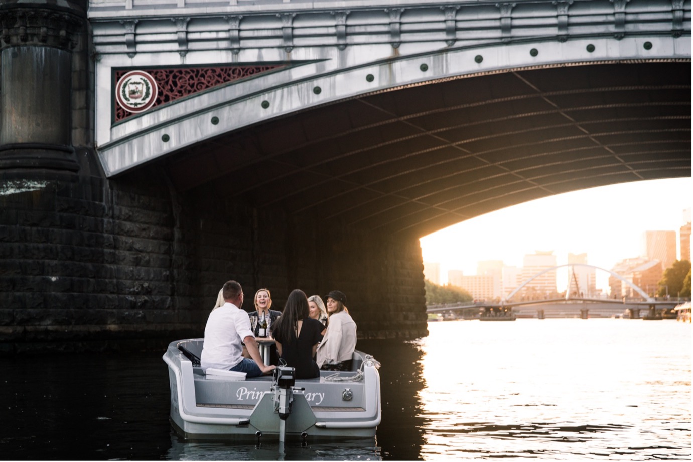 A group of friends cruising on a GoBoat along the Yarra River at sunset in Melbourne.