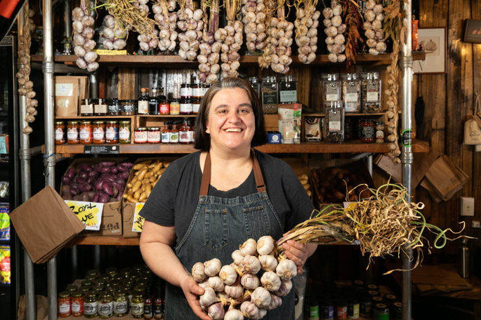 A worker from Georgie's Harvest holding a large bunch of garlic.