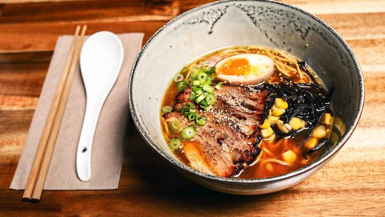 Orange broth sliced meat boiled egg chopped spring inion and corn