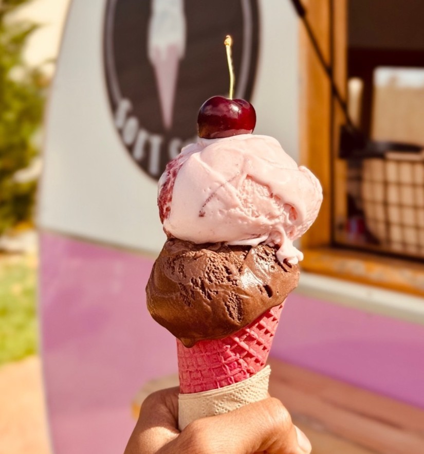 Cherry chocolate and pink ice cream in a pink waffle cone with cherry on top at CherryHill Orchards
