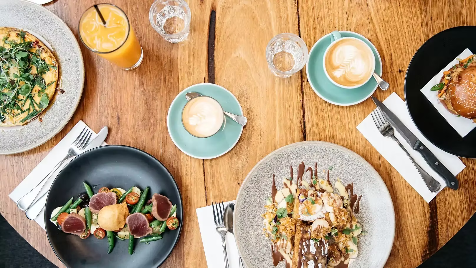 Vibrant brunch plates and coffee from Two Birds One Stone styled on a warm wooden table
