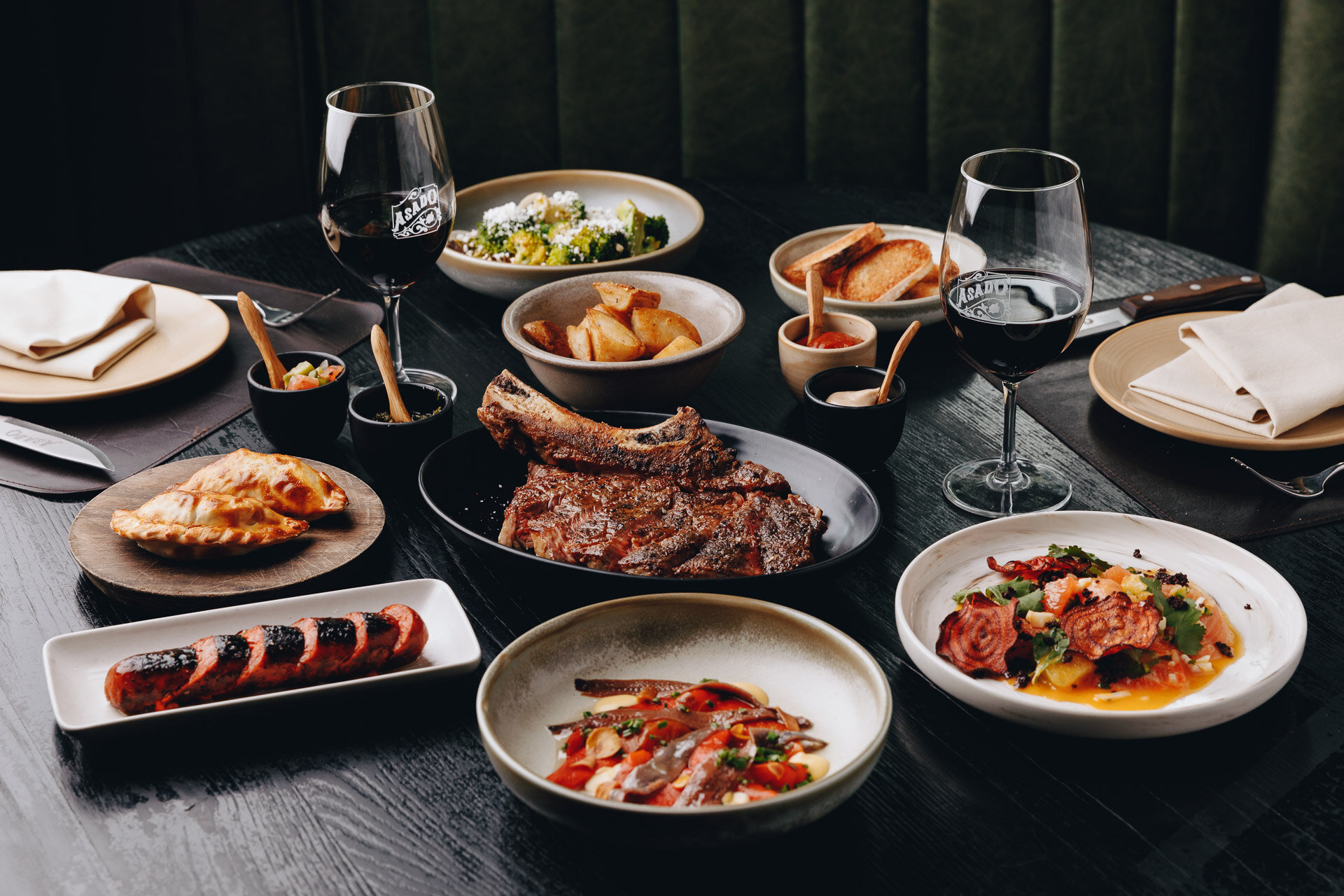 Asado Melbourne — Argentine parrilla steak with chimichurri, chorizos and red wine on dark timber table