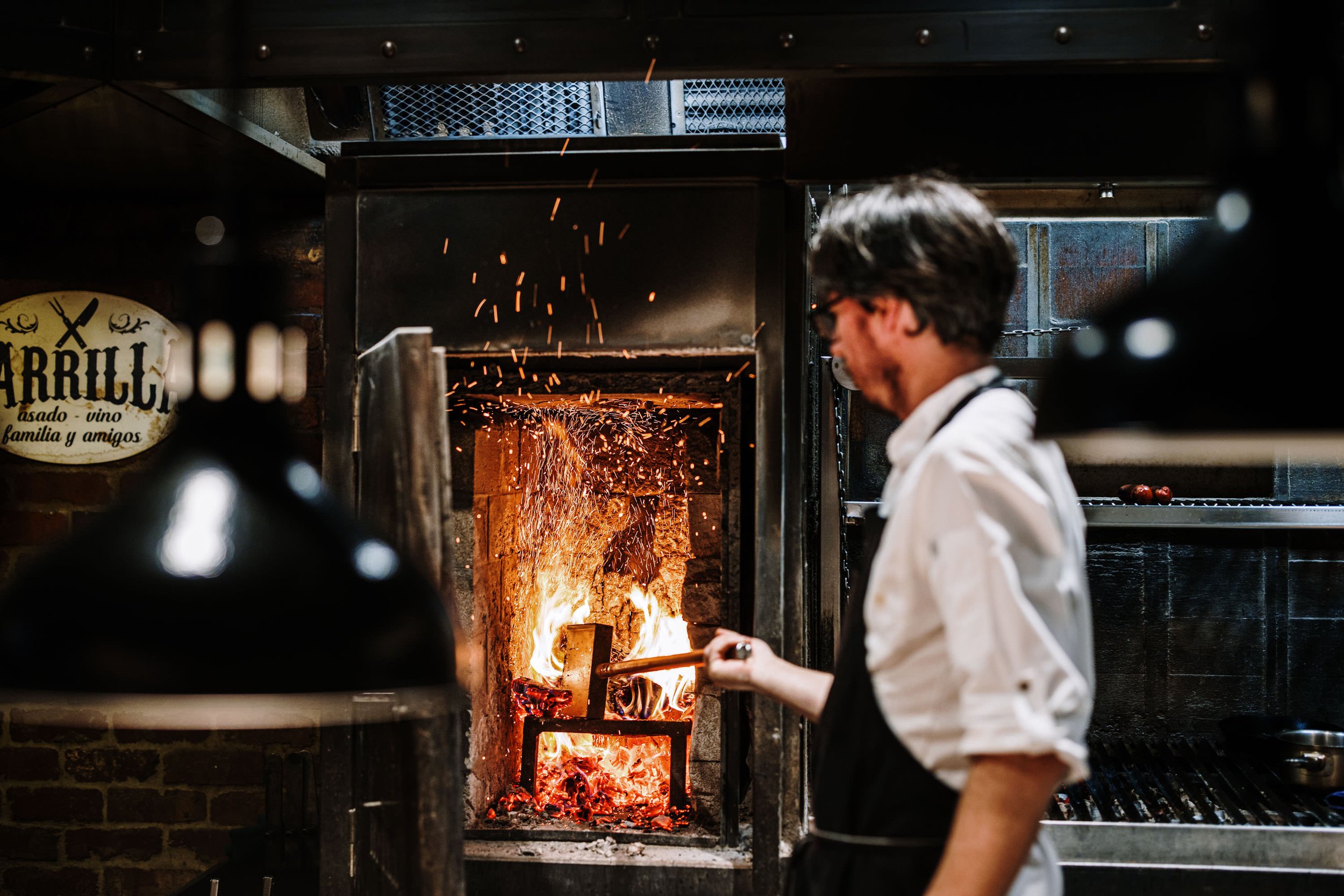 Wood fired parrilla Melbourne — chef tending live fire hearth at Palermo Argentine restaurant Lygon Street