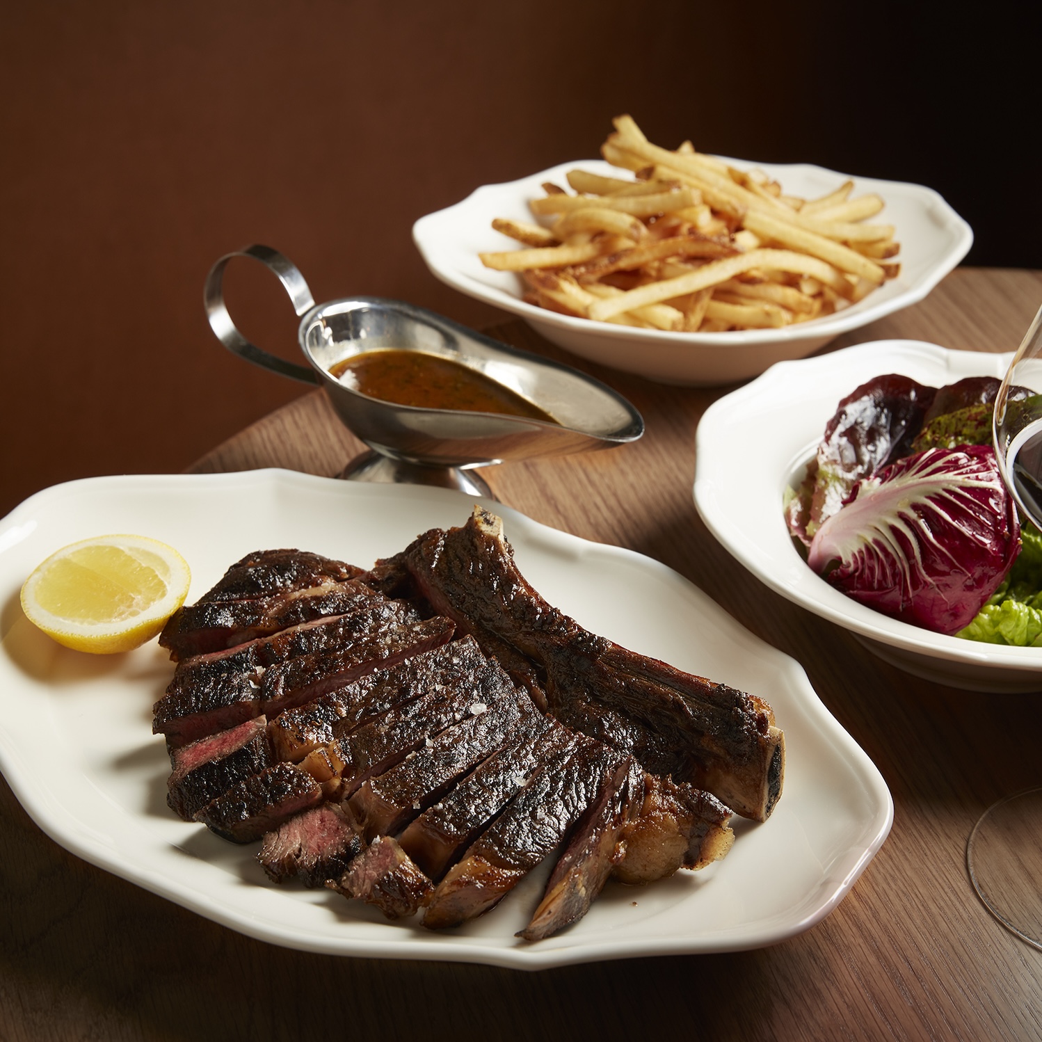 Best wood fired steak Melbourne — sliced charcoal T-bone with frites and salad at Reine & La Rue