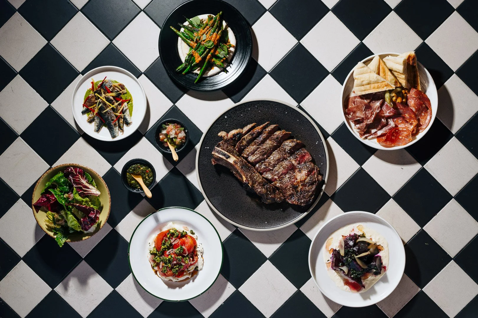 Argentine wood fired steak Melbourne — tomahawk on black and white tiles with chimichurri and share plates at San Telmo