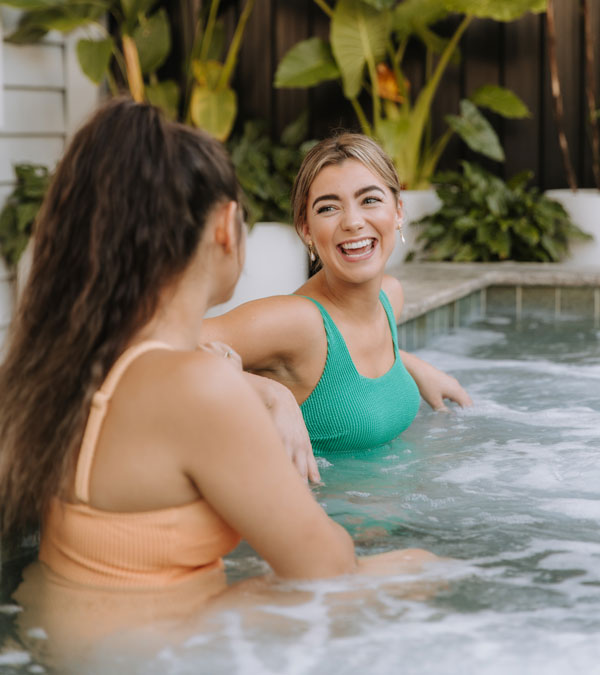 Two women laughing together in the mineral pool spa at Soak Bathhouse South Yarra Melbourne