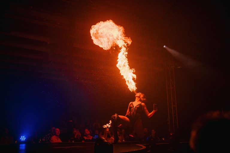 Jacqueline Furey performing with a massive fire fan on stage at Club Kabarett with Berlin neon sign and audience watching