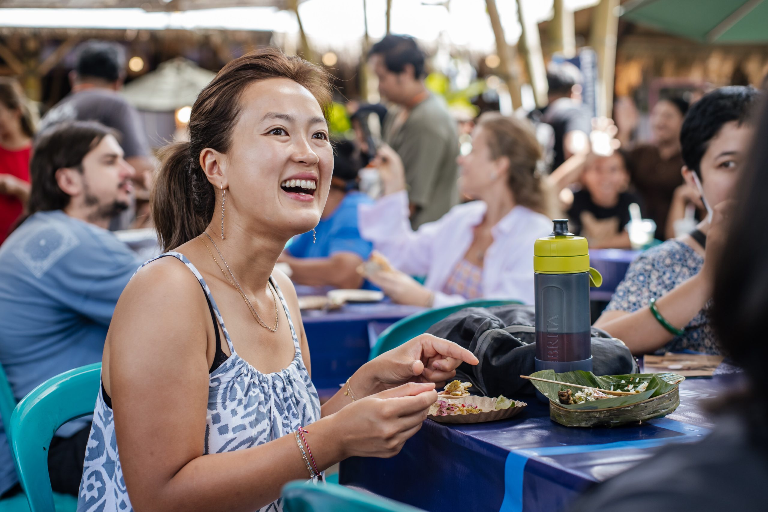 Festival attendee enjoying Indonesian street food at Ubud Food Festival 2026 open air market Ubud Bali