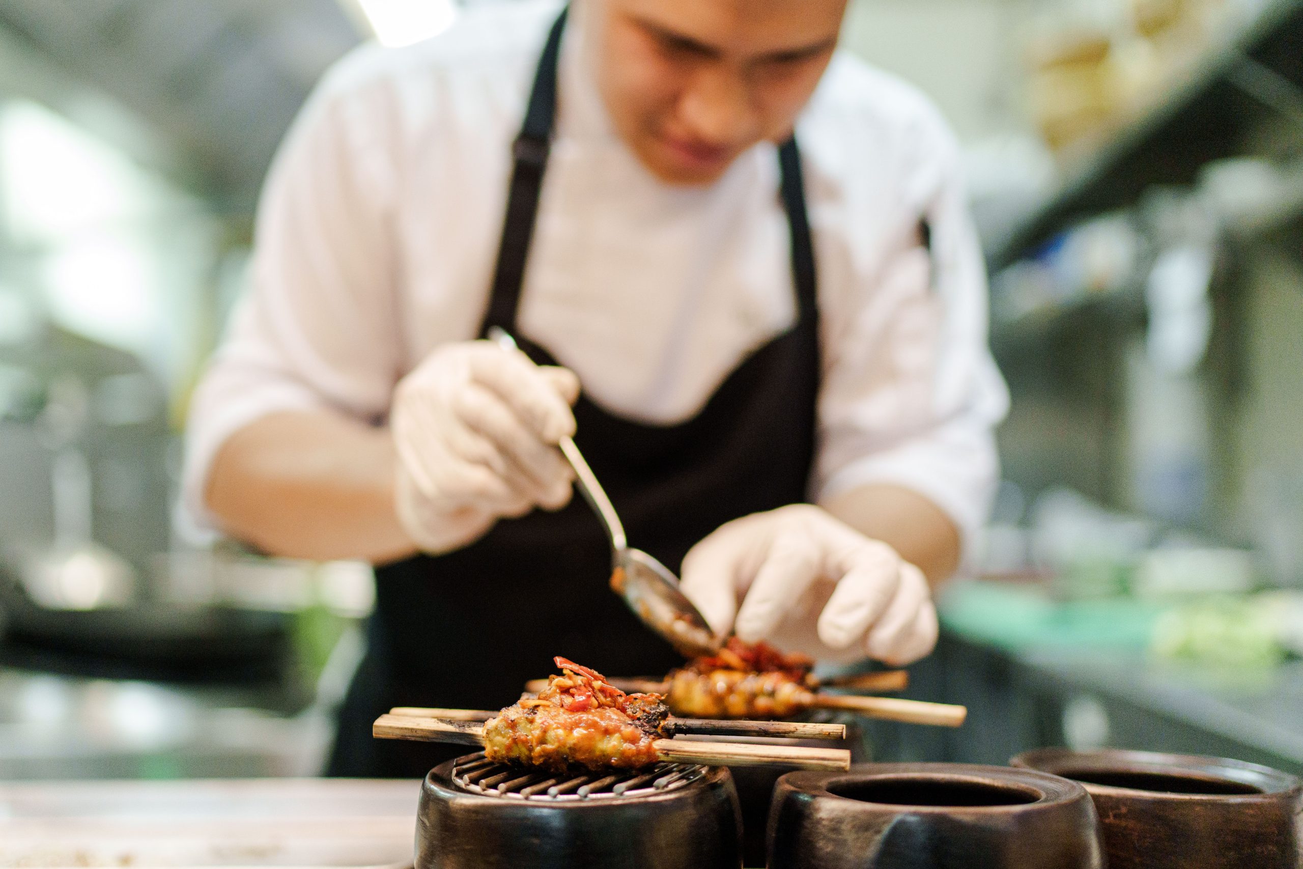 Chef plating traditional Indonesian satay dish at Ubud Food Festival 2026 special dining event Ubud Bali