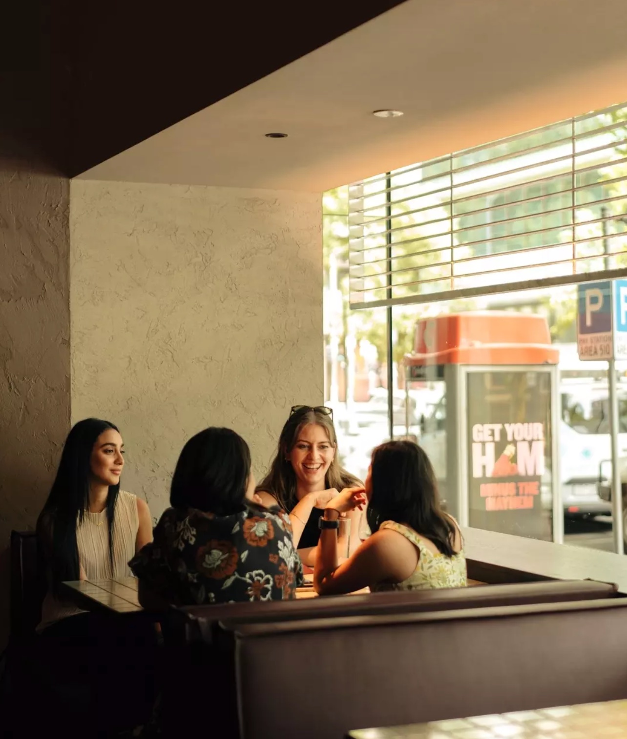 Group of women laughing together over lunch at a Melbourne restaurant, celebrating Mother's Day 2026